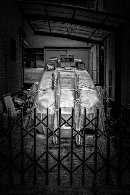 Photograph of a Car with A Tarp atop Held Down with Bamboo